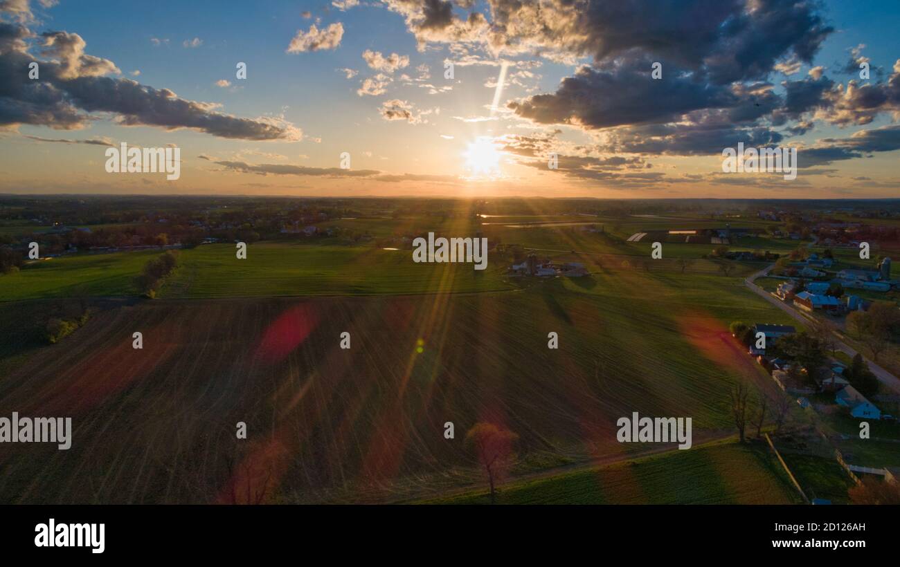 Aerial view of a Sunset over barns, silos and farmlands during the ...