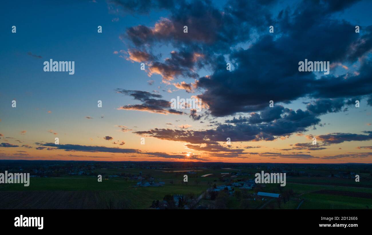 Aerial view of a Sunset over barns, silos and farmlands during the ...