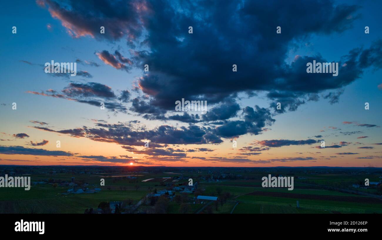 Aerial view of a Sunset over barns, silos and farmlands during the ...