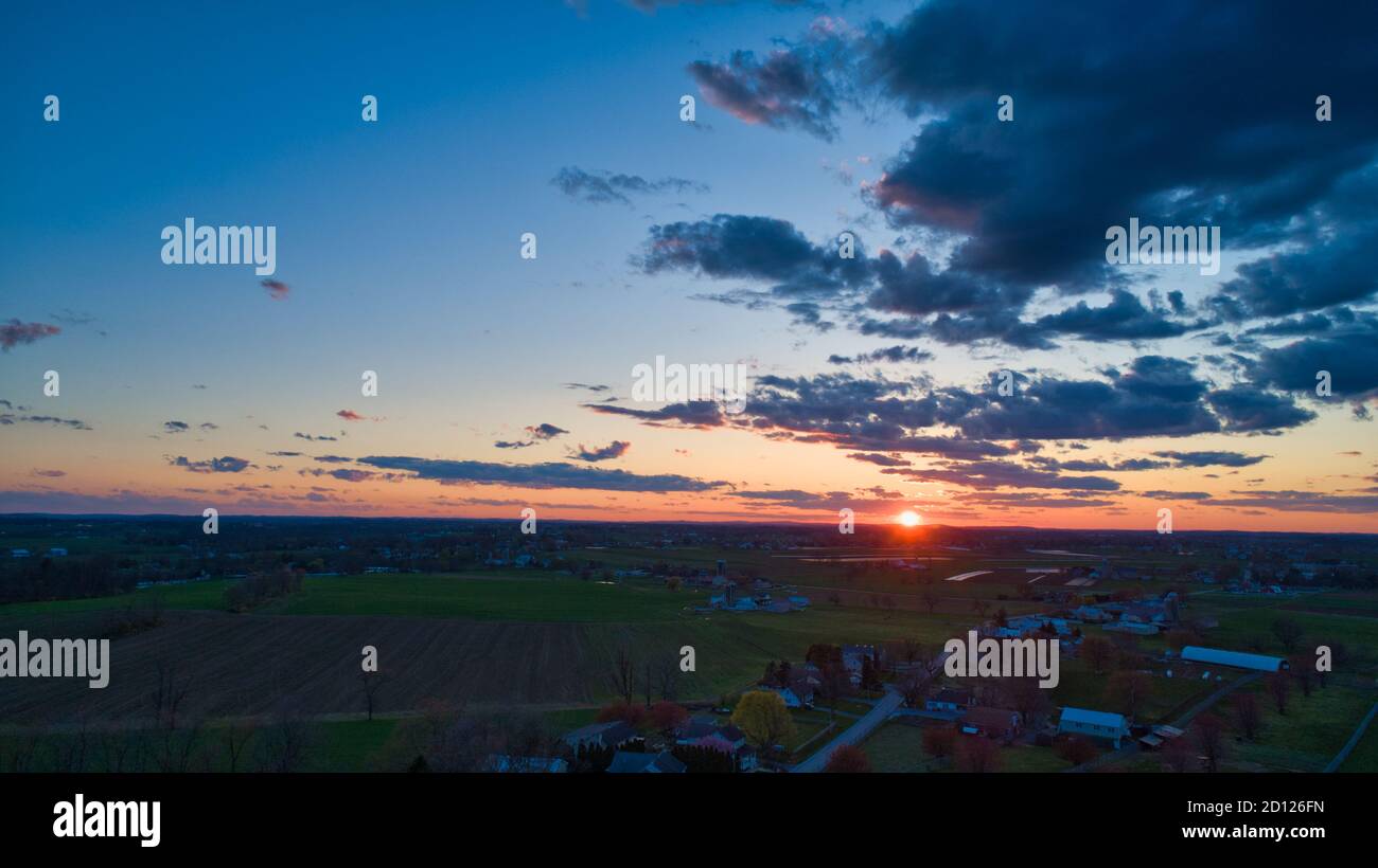 Aerial view of a Sunset over barns, silos and farmlands during the ...