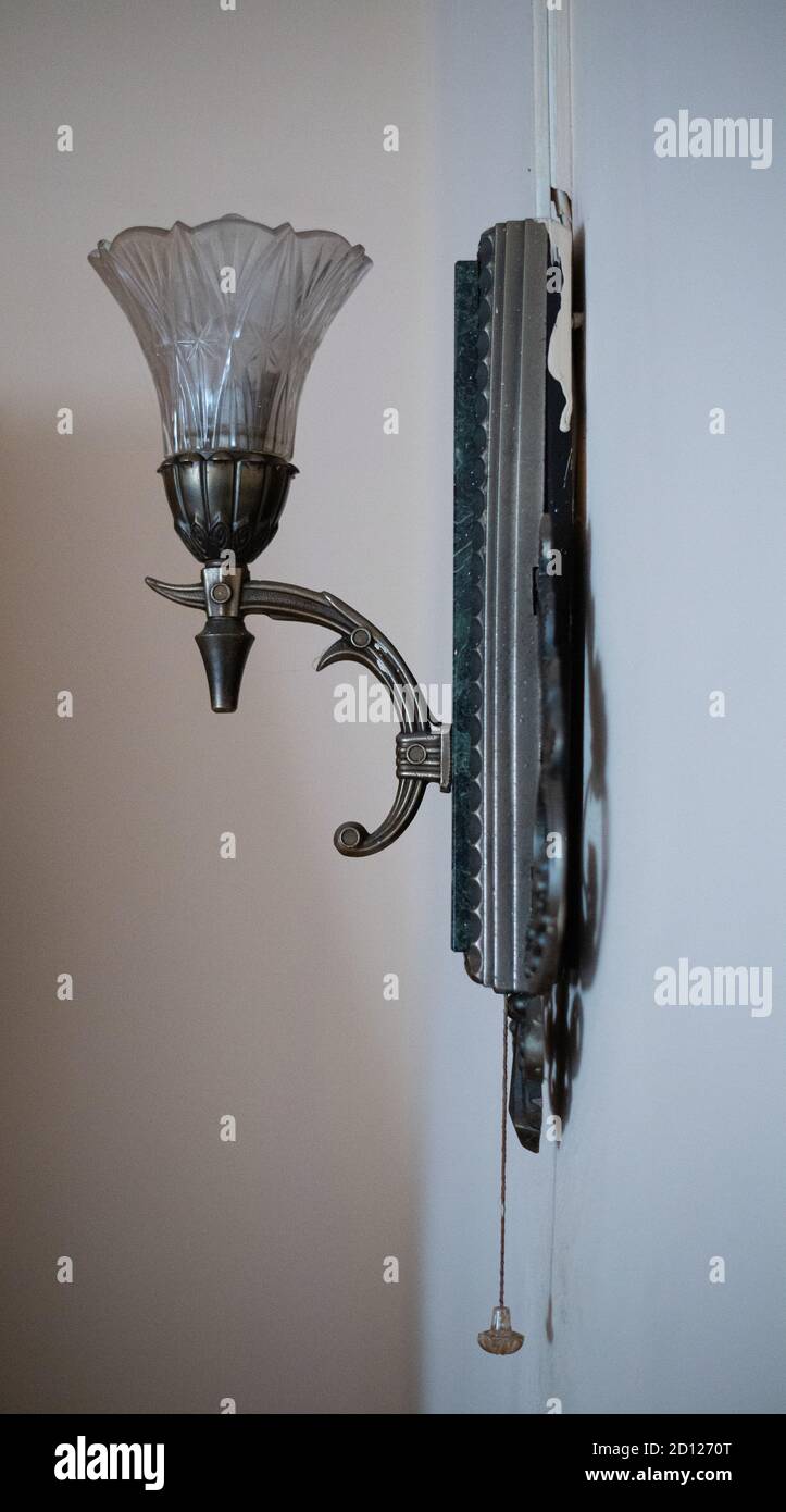 An old bronze sconce with a rope hangs on the wall. Vertically. Stock Photo