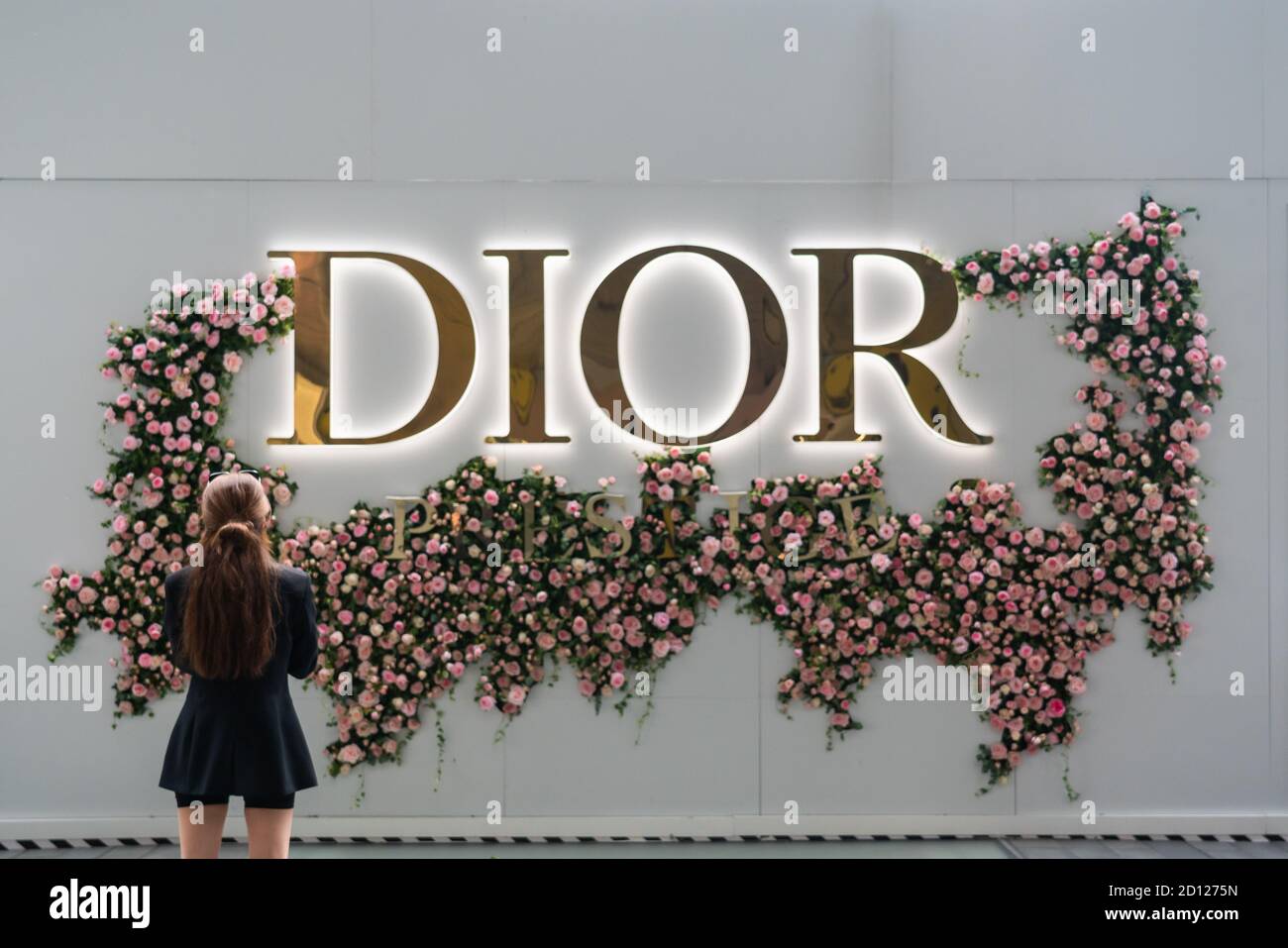 A woman stands in front of a French luxury goods company Christian