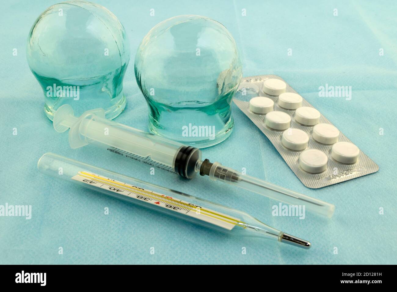 glass massage medical banks, a thermometer, a syringe and pills on a blue medical sheet Stock