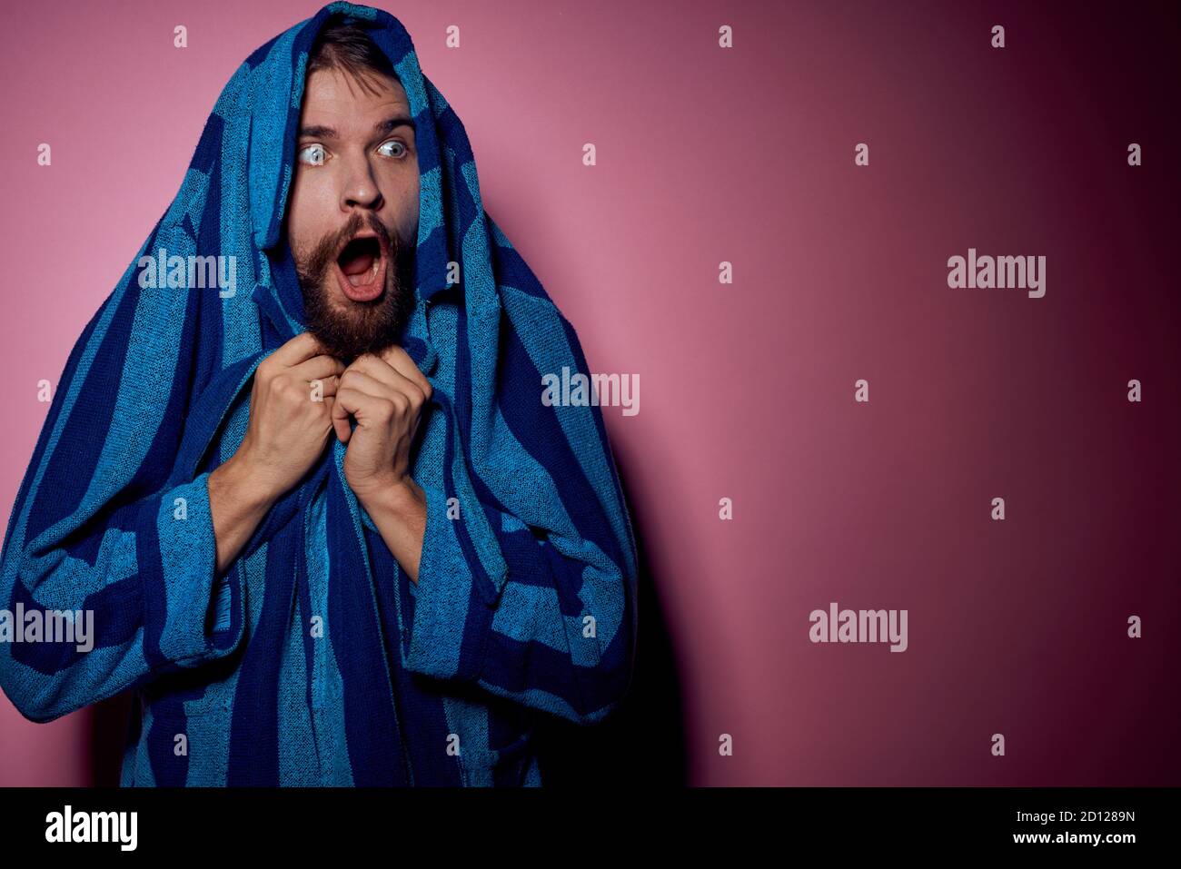 Bearded man in a blue striped robe on a pink background with hands emotions model portrait Stock Photo