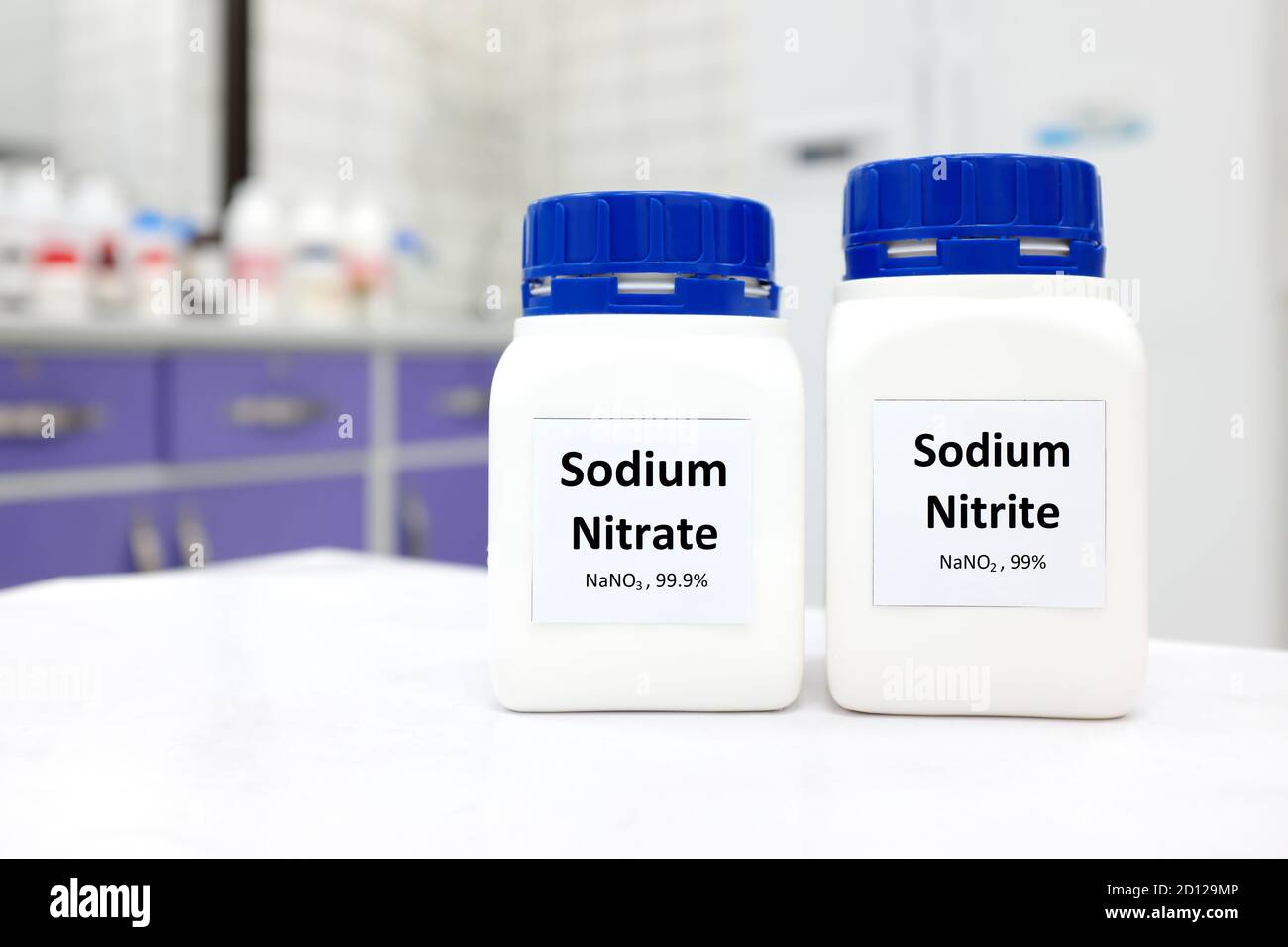 Selective focus of bottles of pure sodium nitrite and nitrate chemical compound preservative. White laboratory background with copy space. Stock Photo