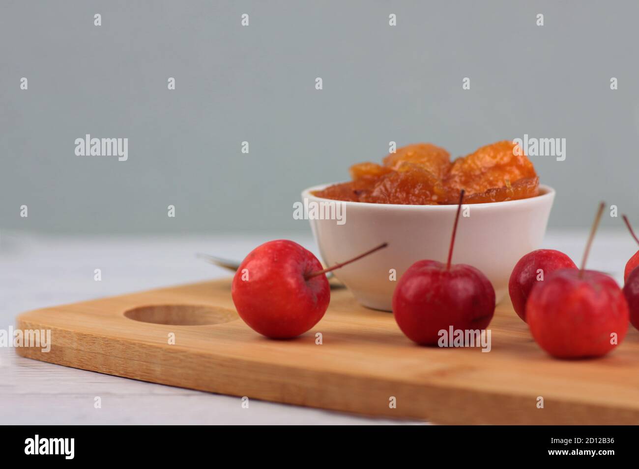 bowl of apple jam and red apples on cutting board against gray background. Image contains copy space Stock Photo