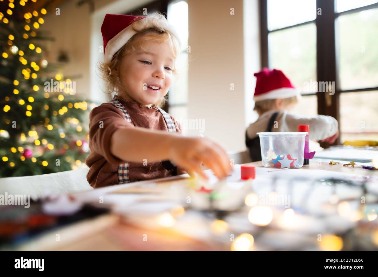 Portrait of small girl and boy indoors at home at Christmas, painting pictures. Stock Photo