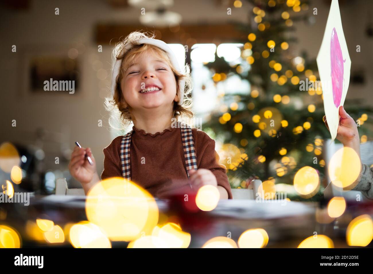 Portrait of small girl indoors at home at Christmas, laughing. Stock Photo