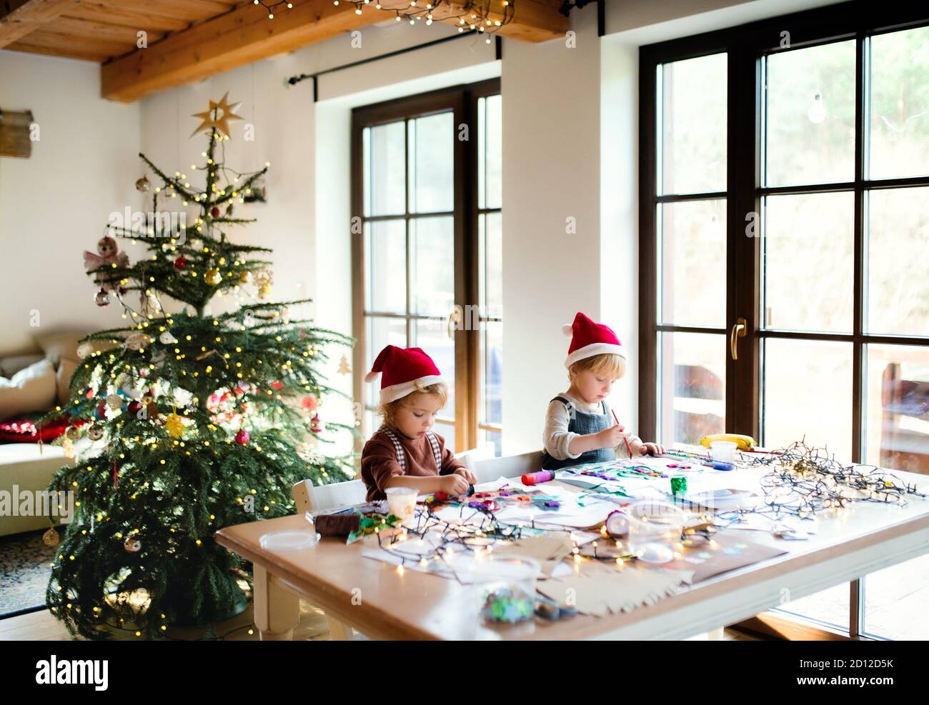 Portrait of small girl and boy indoors at home at Christmas, painting pictures. Stock Photo