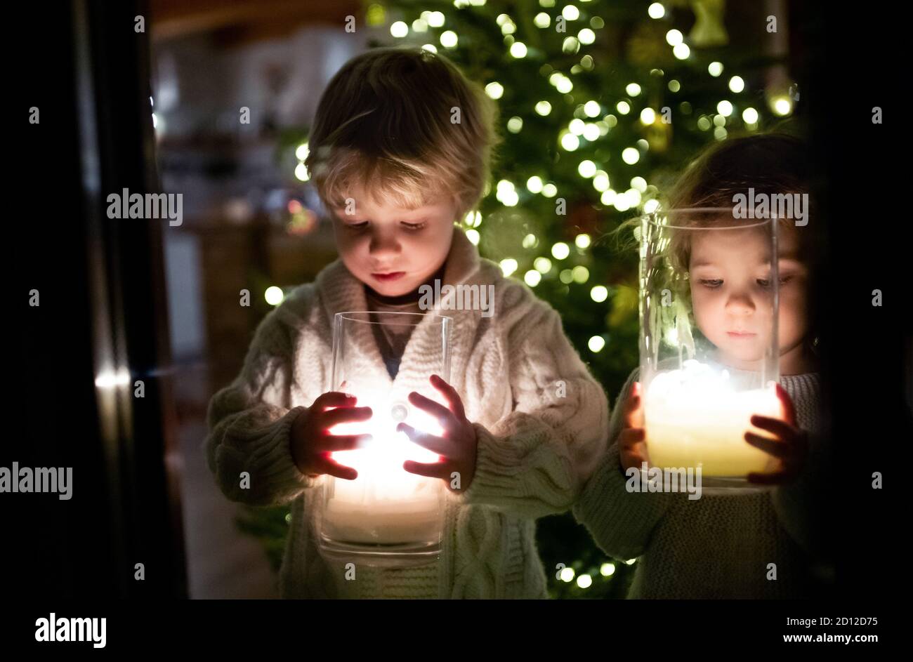 Portrait of small girl and boy indoors at home at Christmas, holding candles. Stock Photo