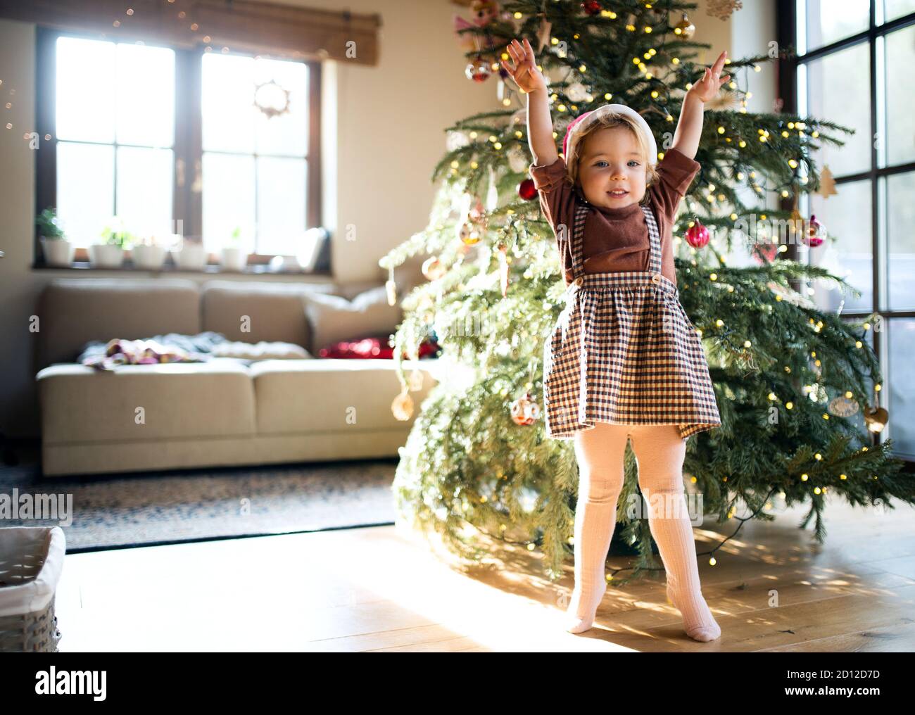 Portrait of small girl indoors at home at Christmas, playing. Stock Photo
