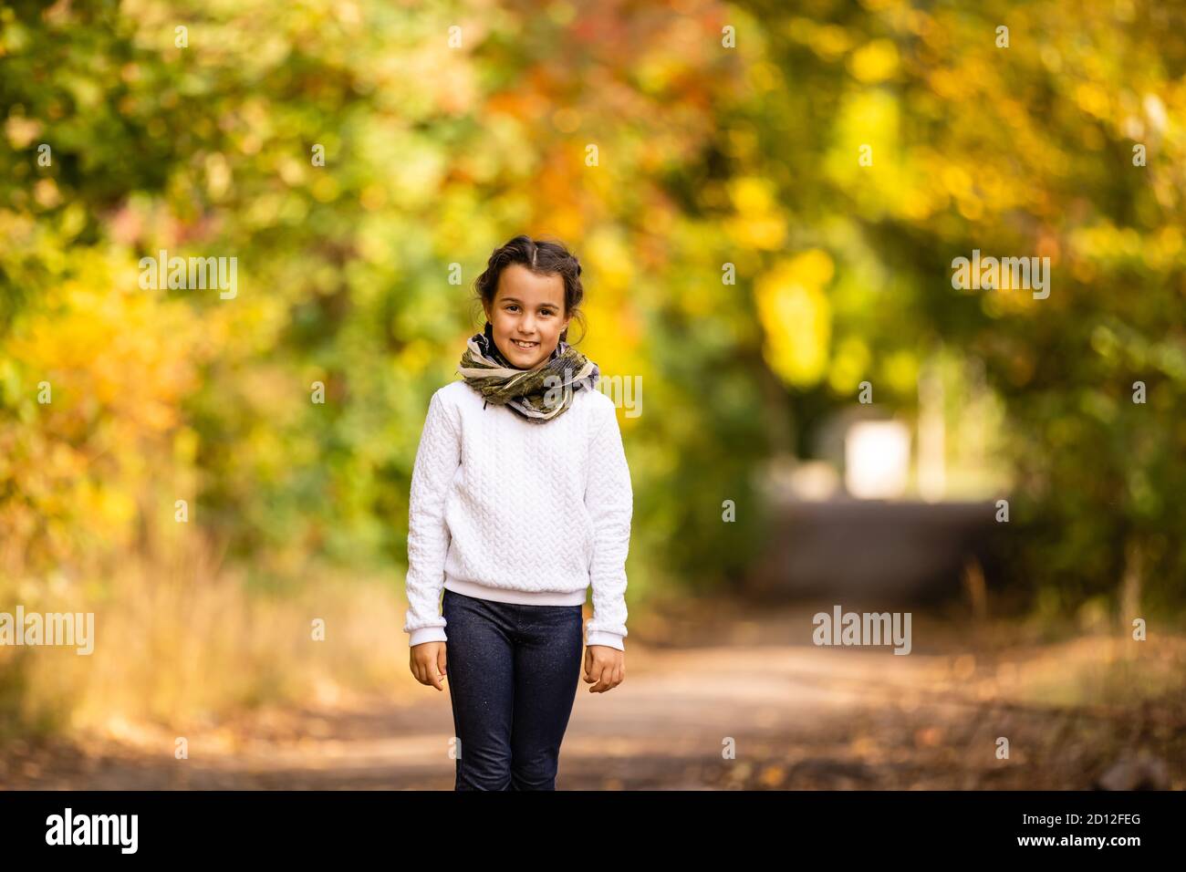 Happy autumn! Little sweet girl playing with leaves in an autumn park ...