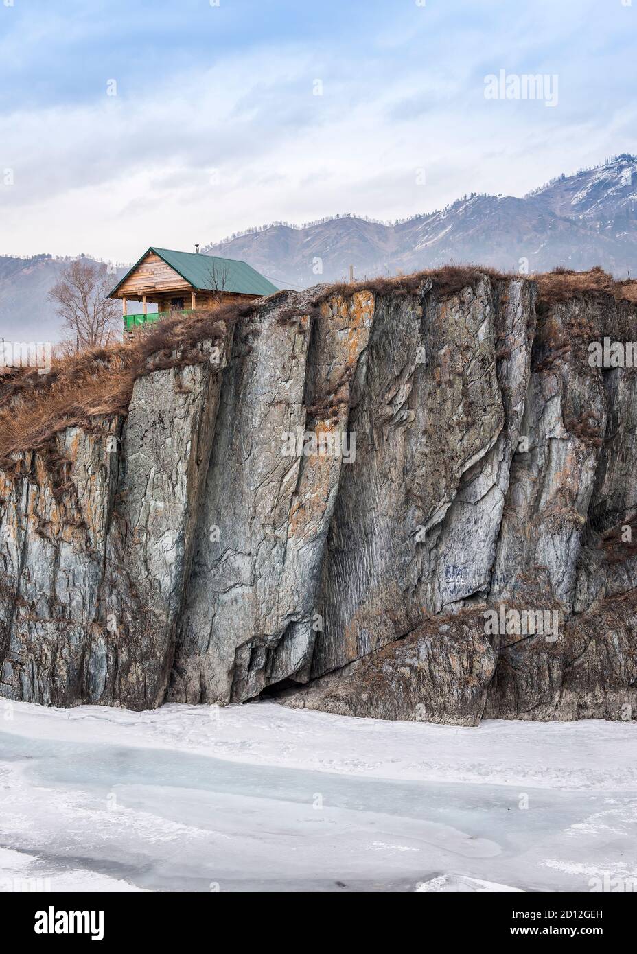 A small house on a cliff on Katun River covered by ice in Mountain Altai region of Russia Stock Photo