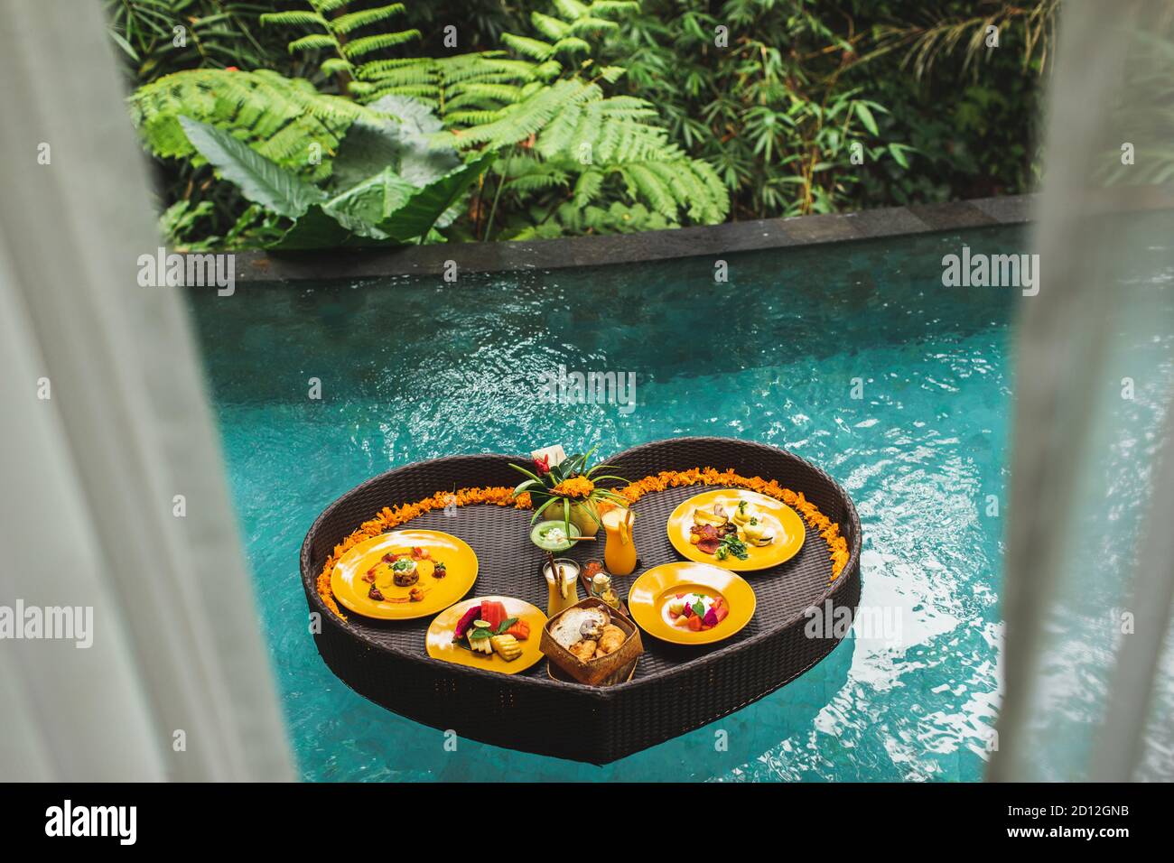 Floating breakfast in jungle swimming pool, tropical resort. Black ...