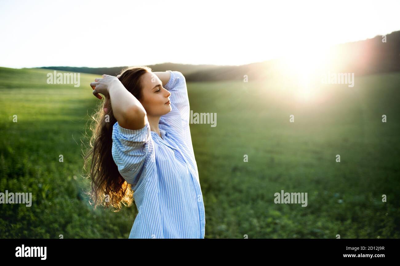 Portrait of young teenager girl outdoors in nature on meadow at sunset. Stock Photo