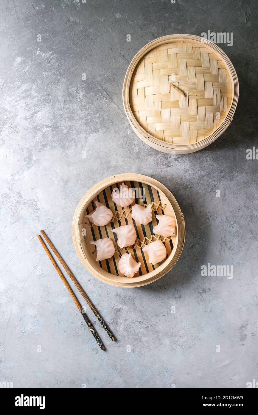Asian steam potstickers dumplings stuffed by shrimps in opened bamboo steamer with chopsticks