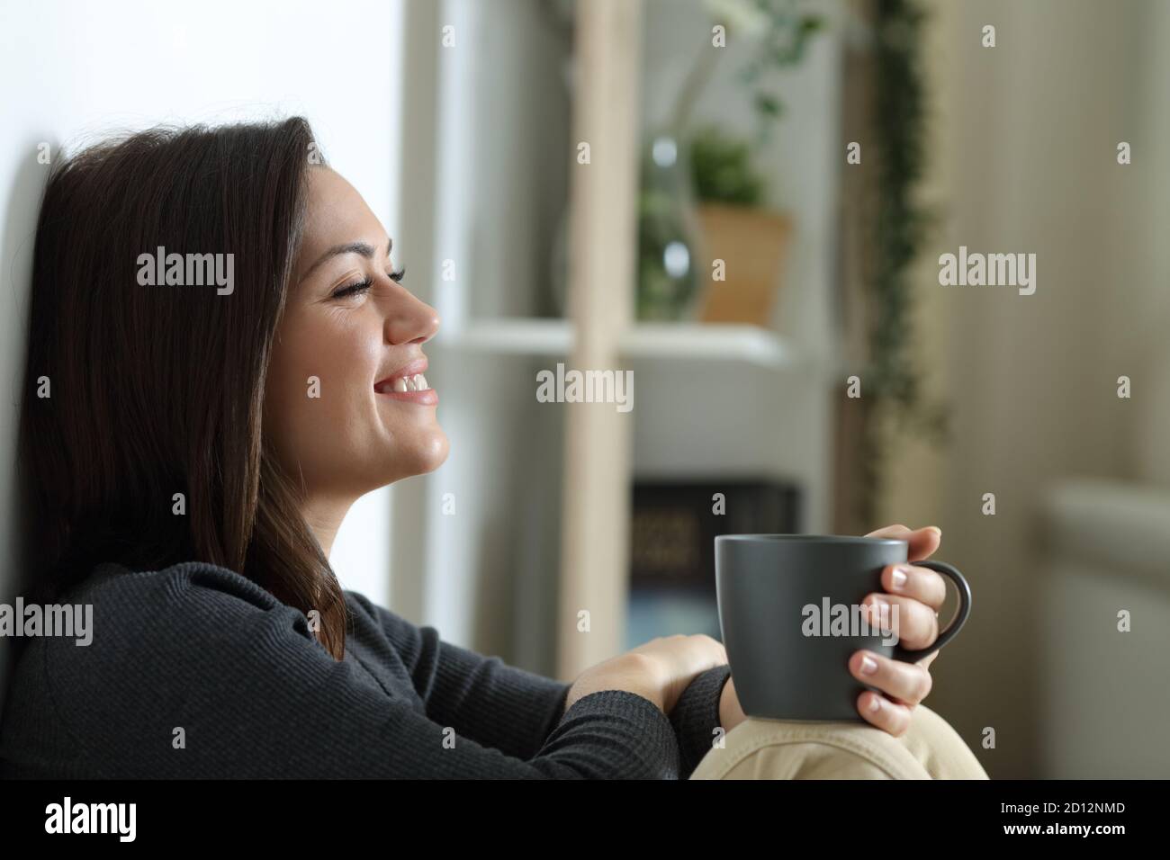 Happy woman smiling alone sitting on the floor at home in the night Stock Photo