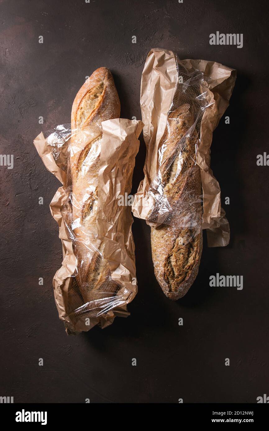 Two loafs of fresh baked artisan rye and white bread in market paper ...