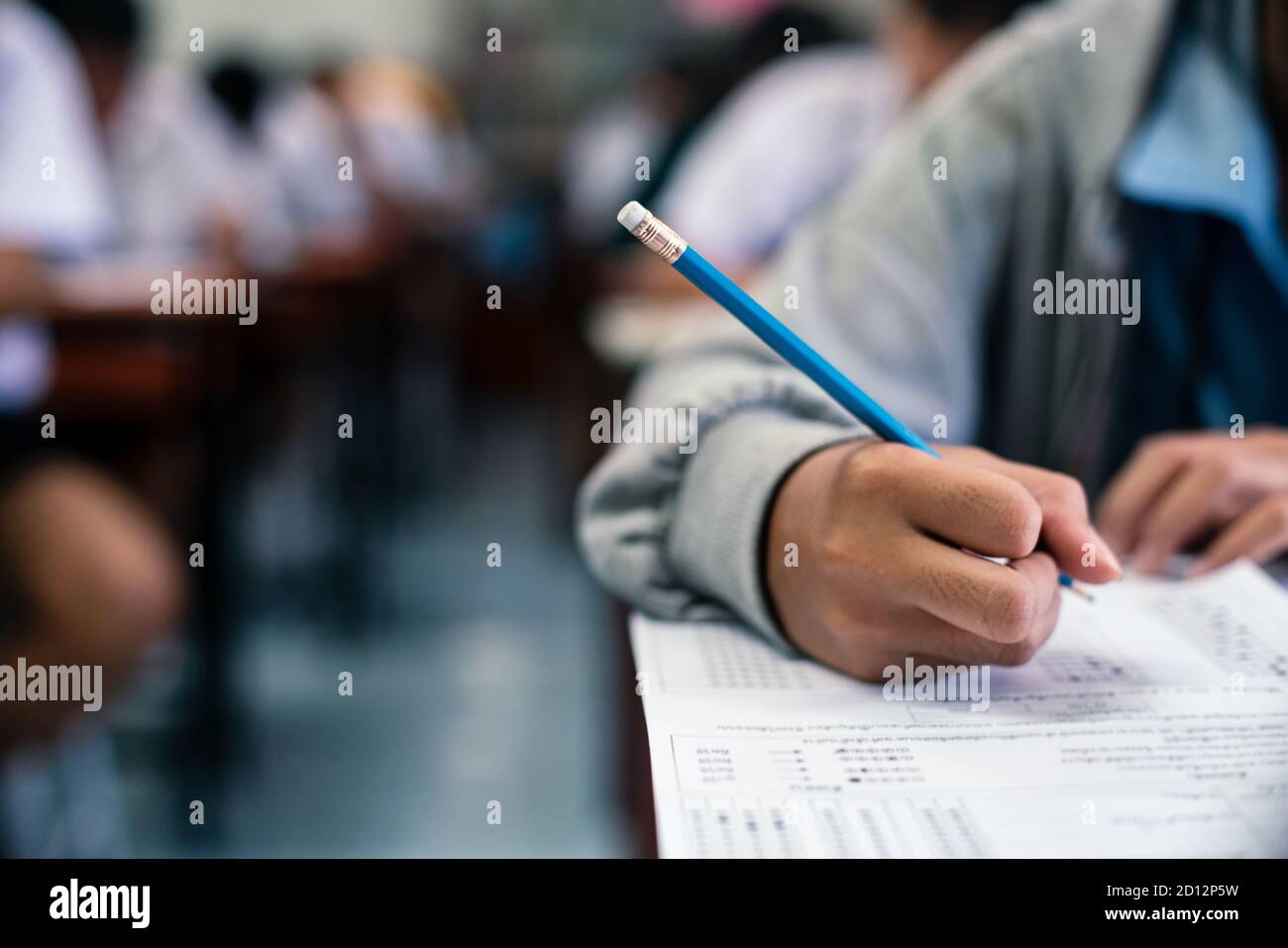 Students writing and reading exam answer sheets exercises in classroom ...