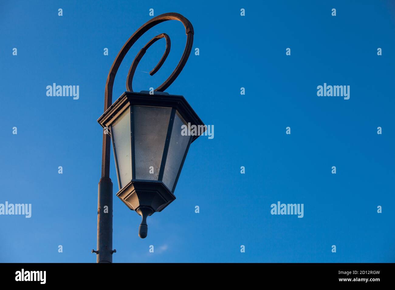 Low-angle view of antique style lampposts against a bright blue sky. Stock Photo