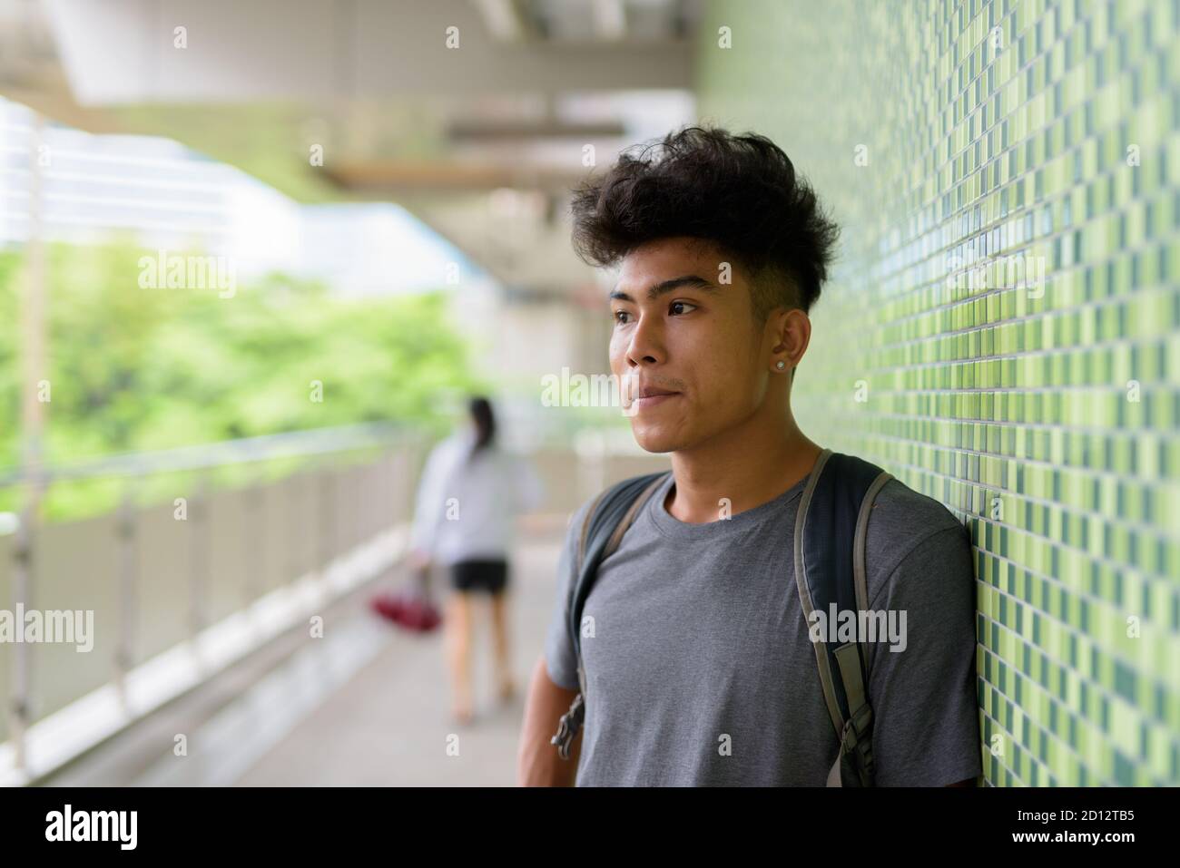 Young Asian tourist man as backpacker thinking at the footbridge Stock Photo