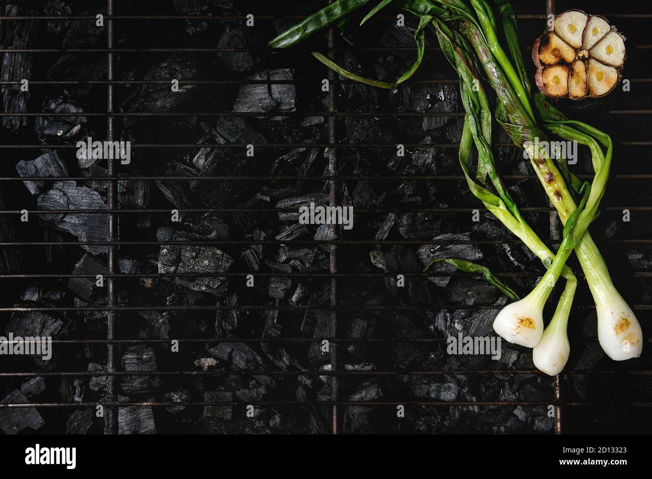 Grilled vegetables spring onion and garlic on bbq grill rack over