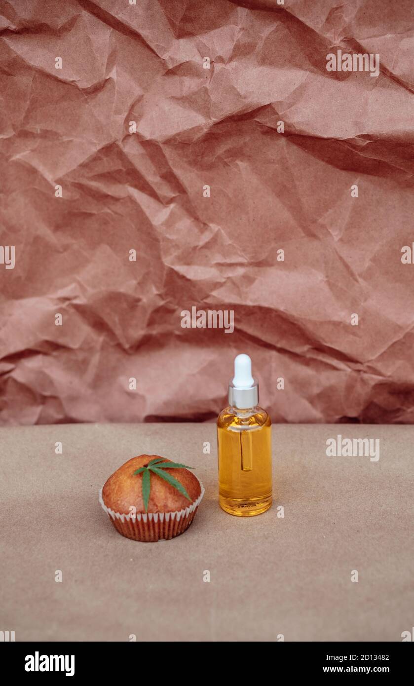 Glass bottle and dropper of CBD oil, cookie and hemp leaf on a kraft