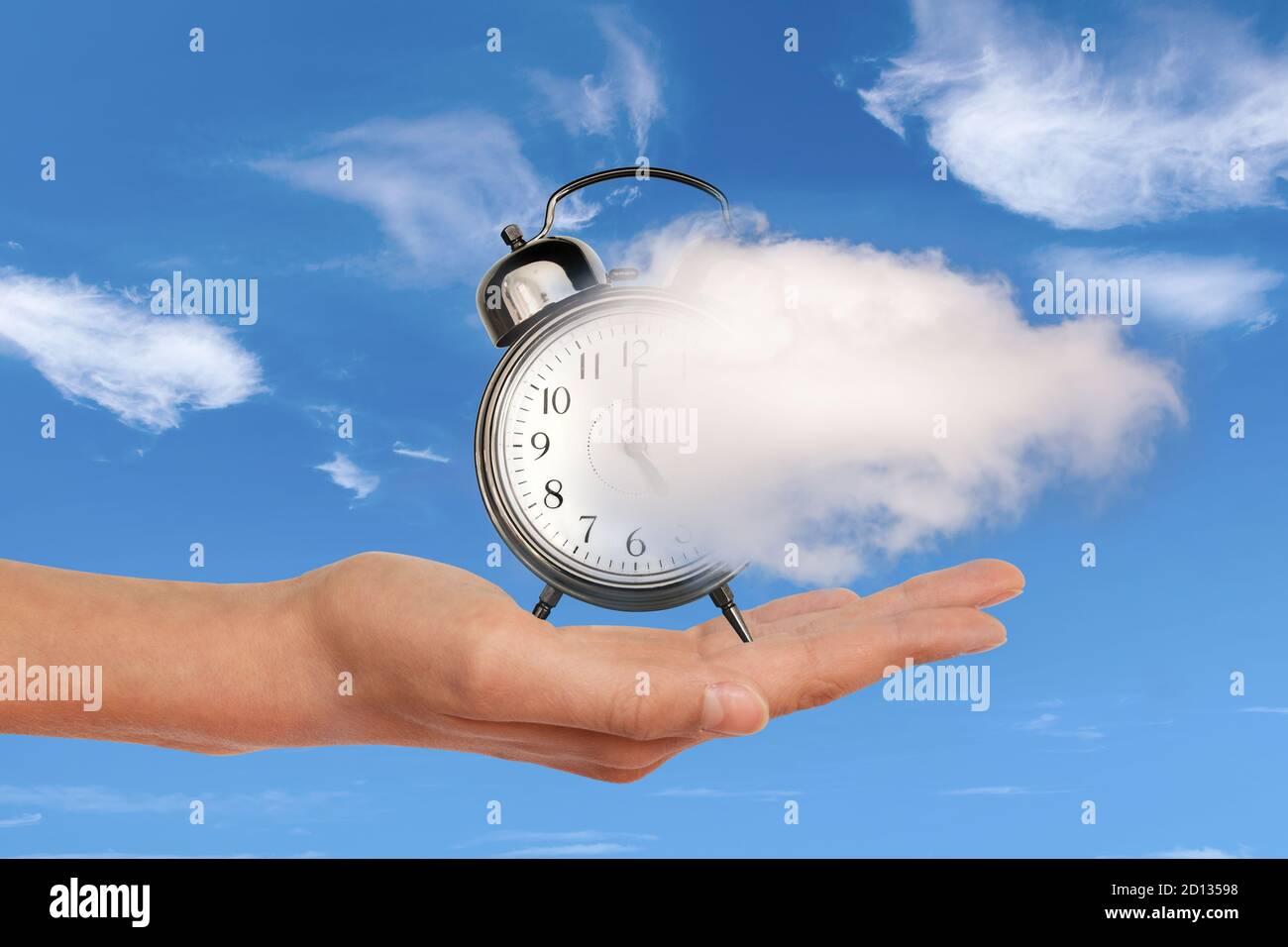 Hand holding a clock dissolving away in a cloud. Time flies, time management concept. Surreal collage. Stock Photo