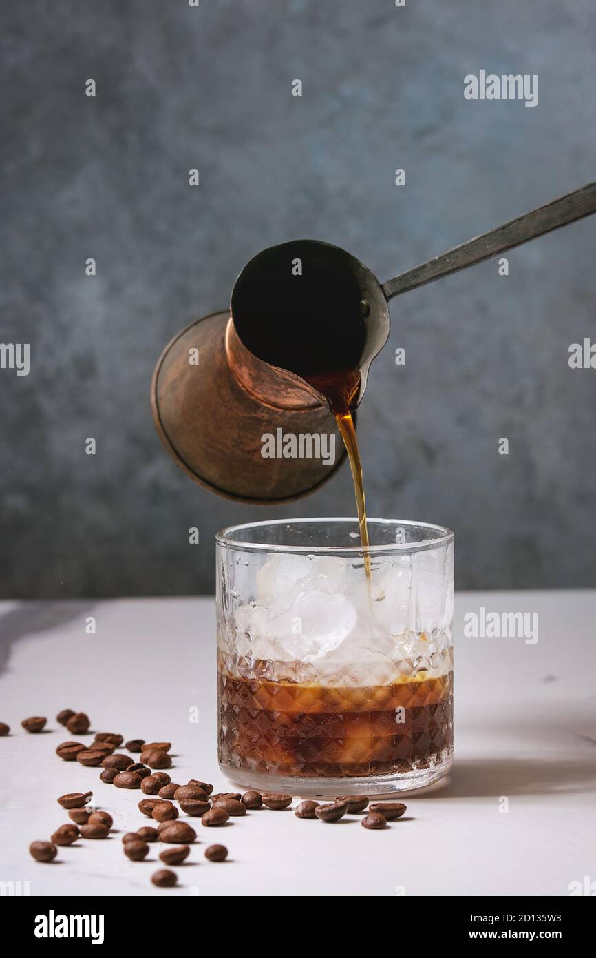 pour the frappe from the shaker into a tall glass , beautiful and clean  composition with coffee beans and amaretti biscuits Stock Photo - Alamy