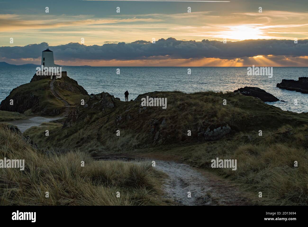 Photographer getting a shot of the lighthouse at Llanddwyn, Anglesey, Wales at sunset. Stock Photo