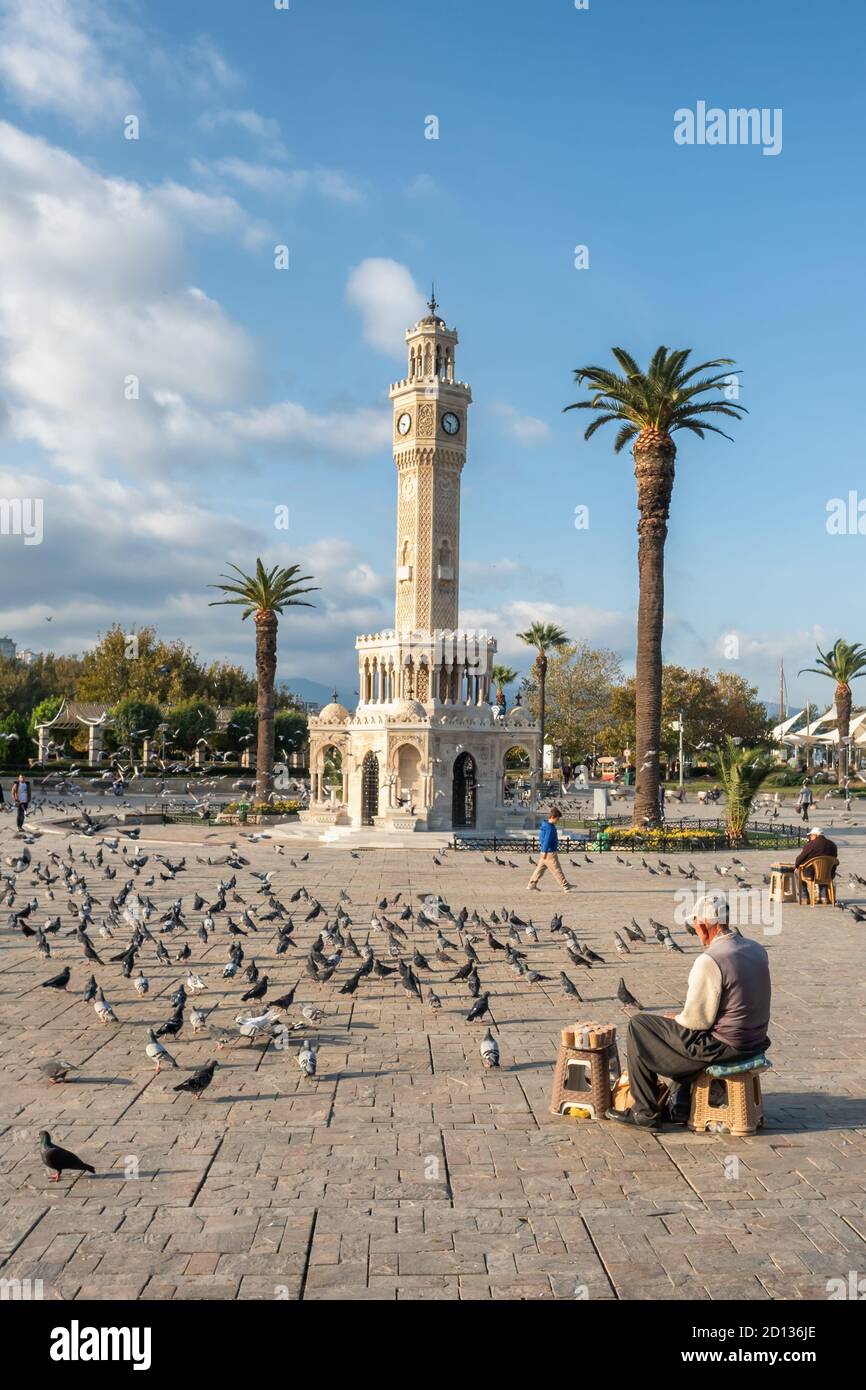 Unidentified turkish senior man selling food for pigeons near the Clock Tower of Izmir at Konak Square in Turkey Stock Photo