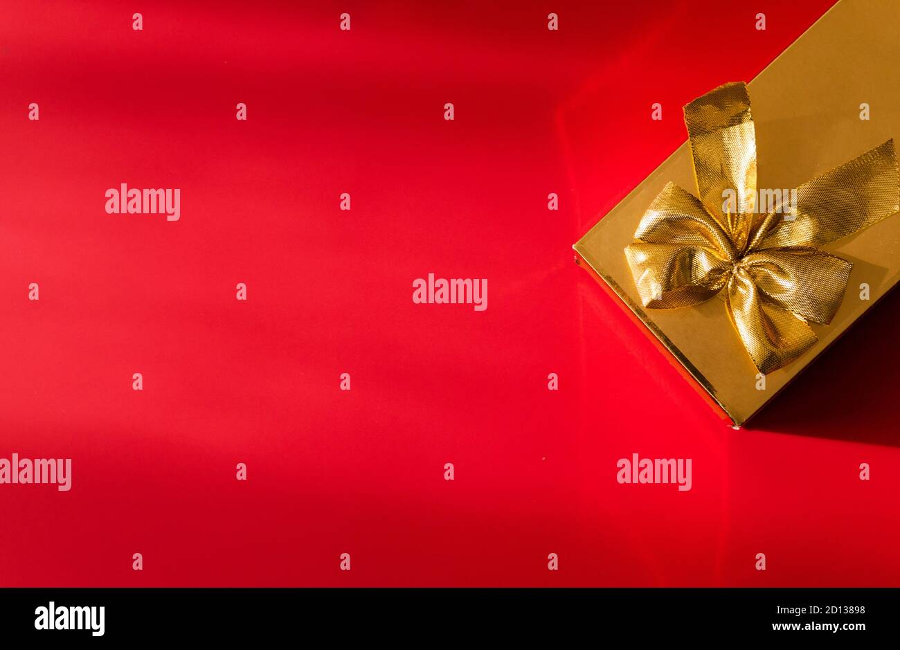 Gold color gift wrap with gold bow on red background Stock Photo Alamy