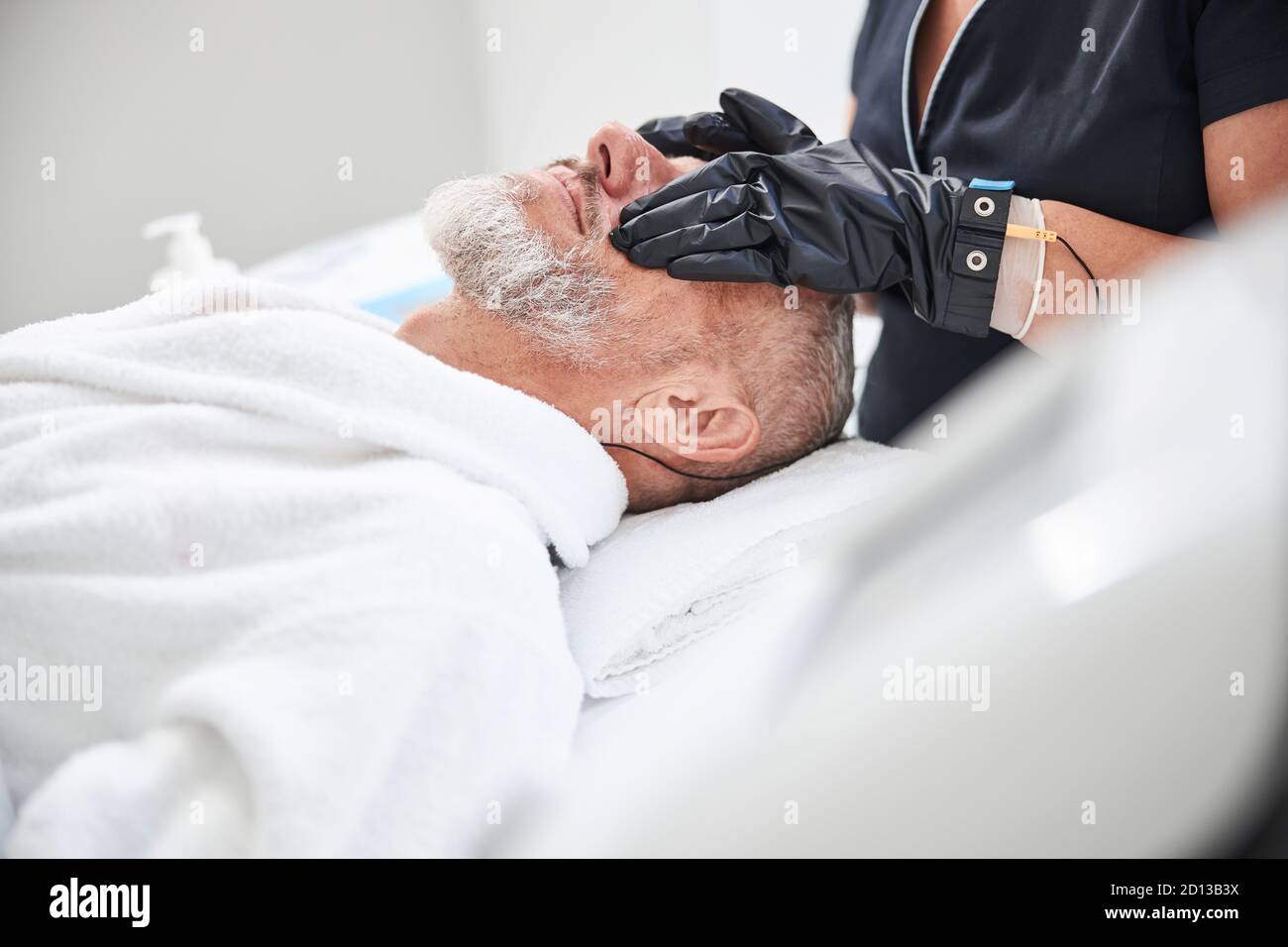 Spa therapist wearing gloves during a facial massage Stock Photo Alamy