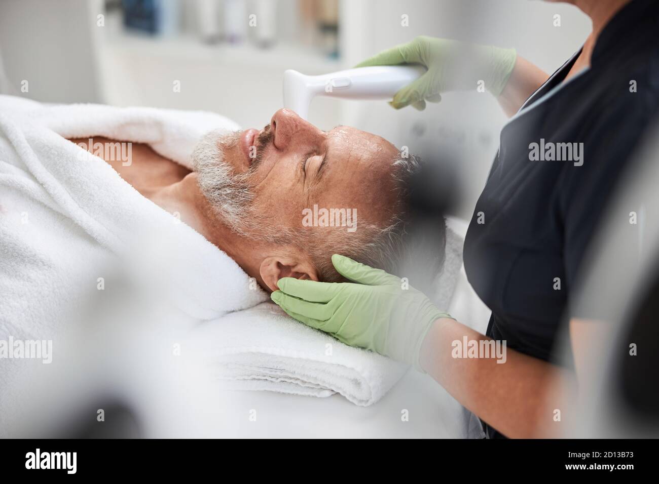 Aging man looking chilled at a skincare treatment session Stock Photo