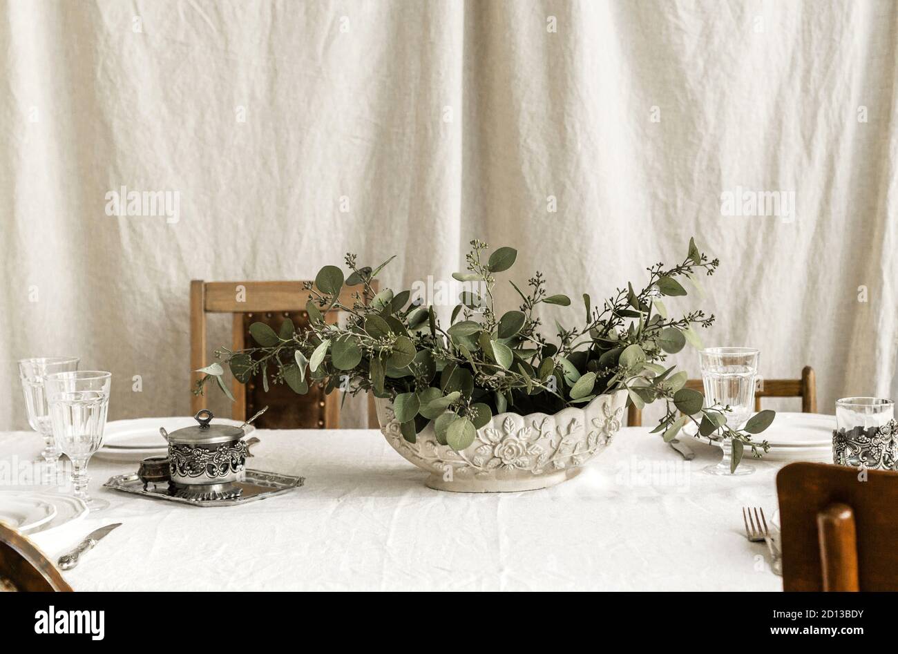 Decorated boho table. The table is covered with a tablecloth, plates, glasses and a vase with a green plant Stock Photo