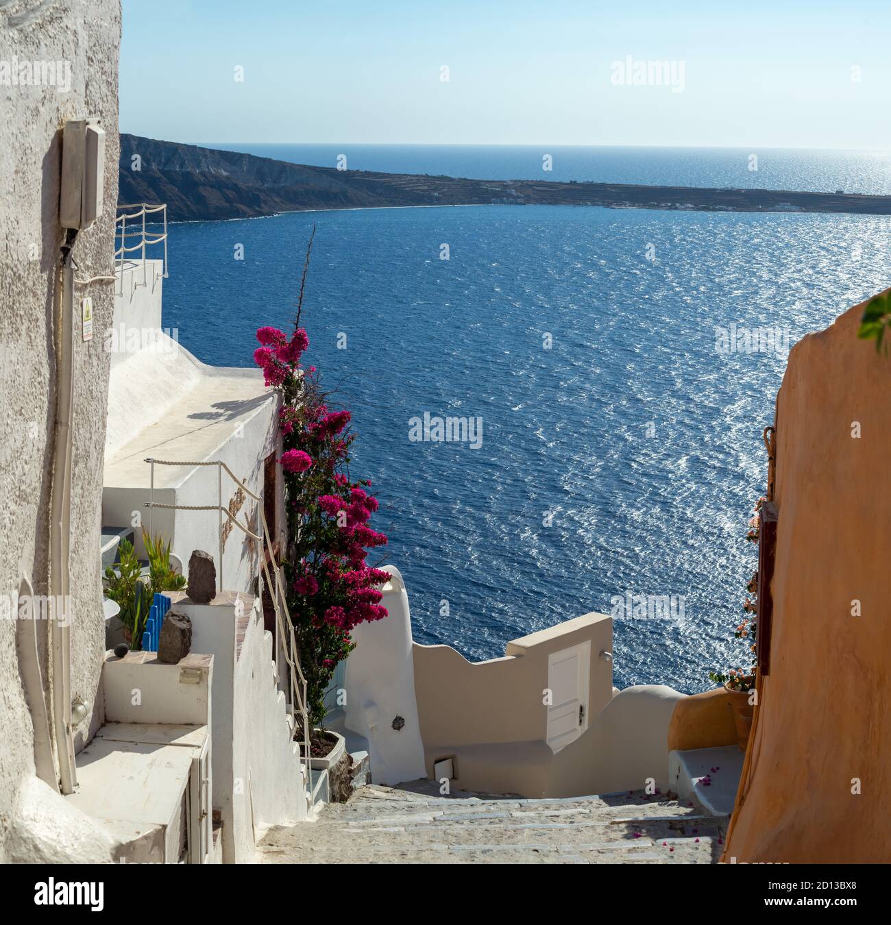 Street of Oia town in Santorini island with bougainvilleas, old whitewashed houses and stairs, Greece landscape on a sunny day Stock Photo