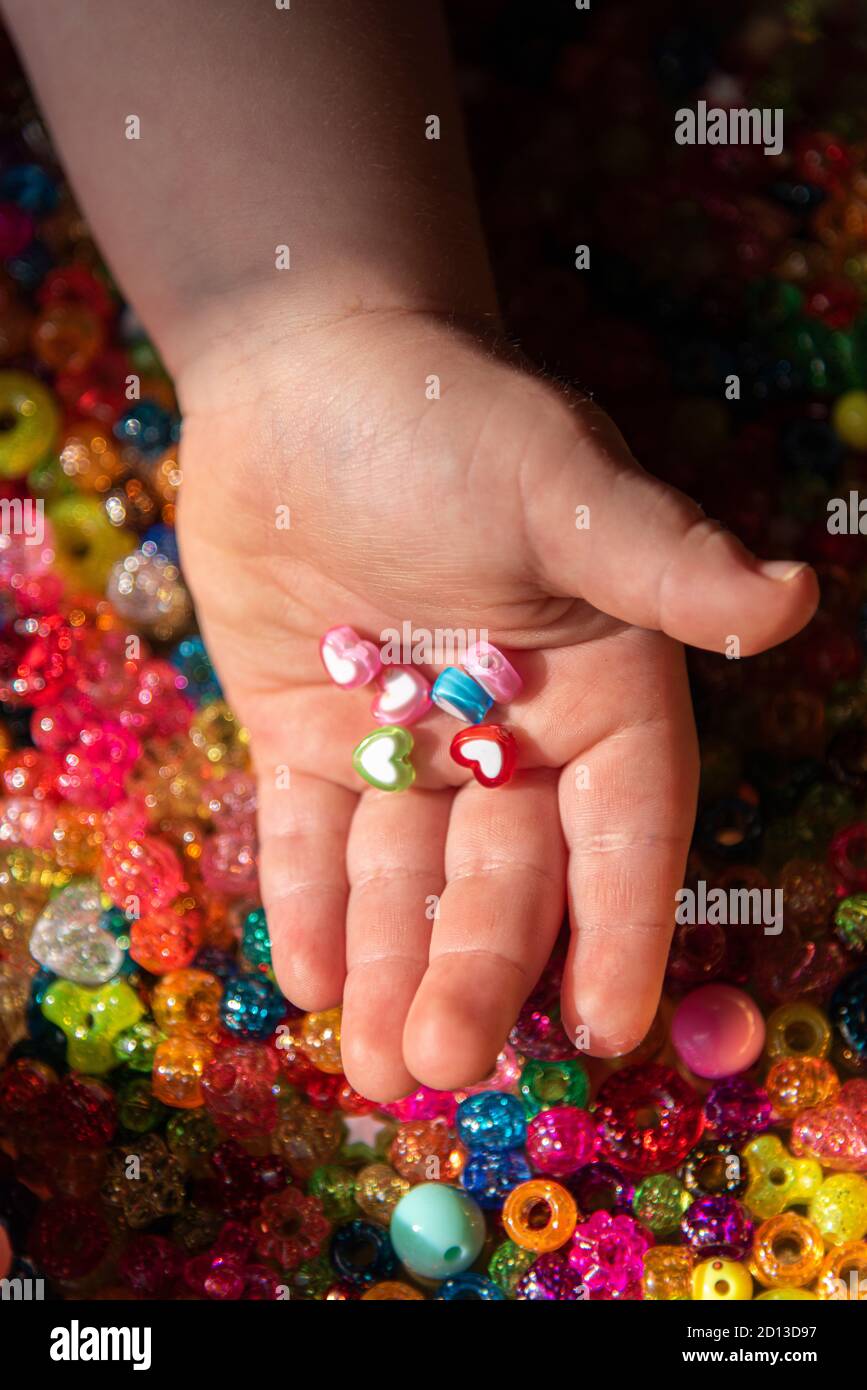 Colored beads in child's palms. A very colorful background of sparkling beads Stock Photo