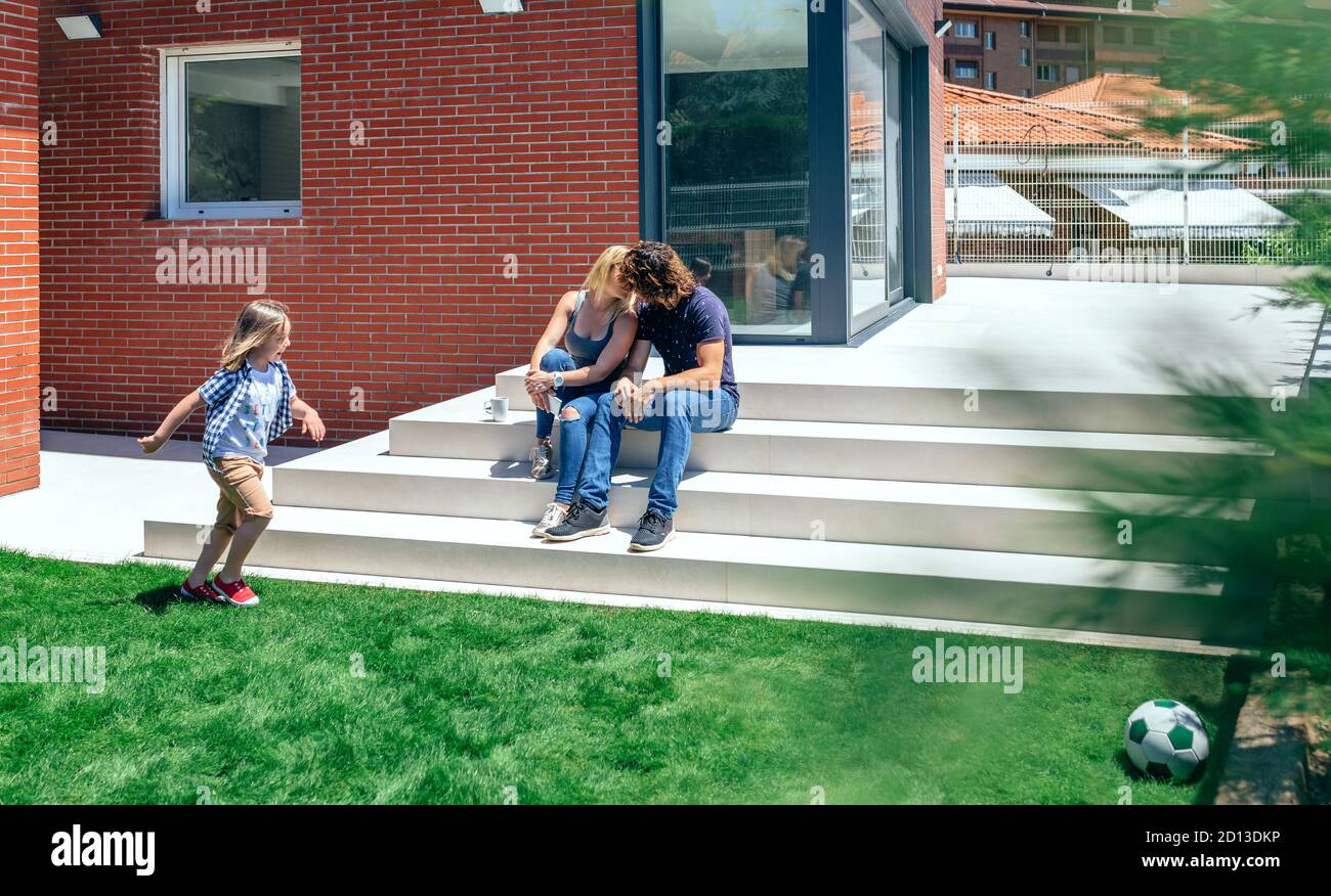 Couple kissing in front new house with son playing Stock Photo Alamy