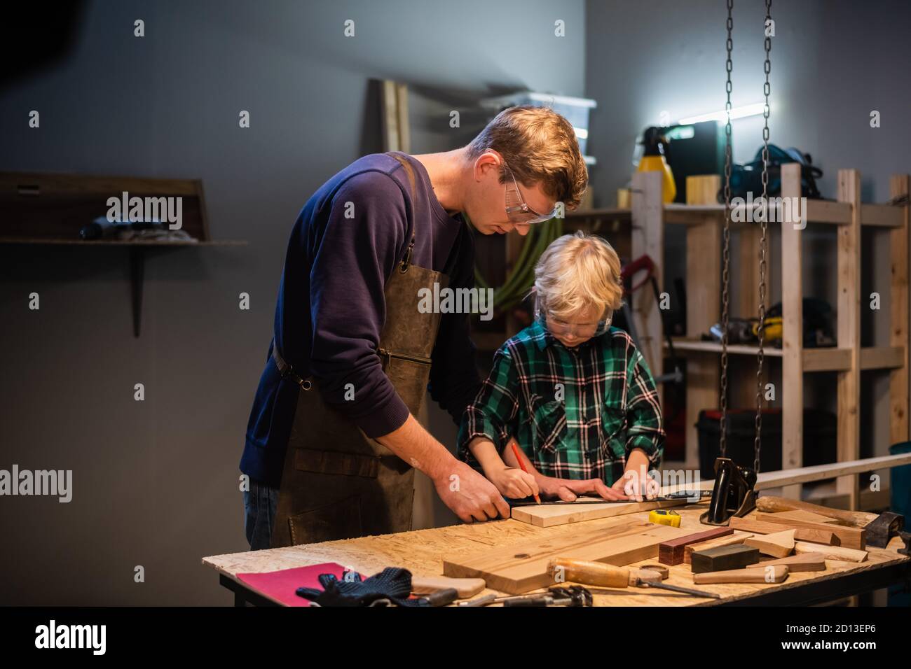 an experienced carpenter and his young apprentice make wood crafts in