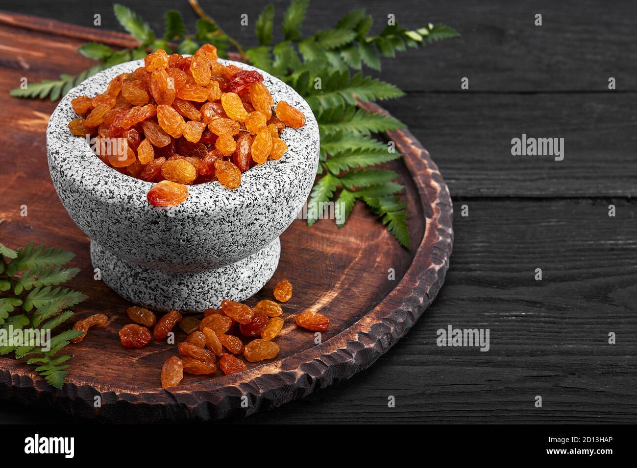 Close up of yellow raisins in a stone bowl, close up, dark background ...