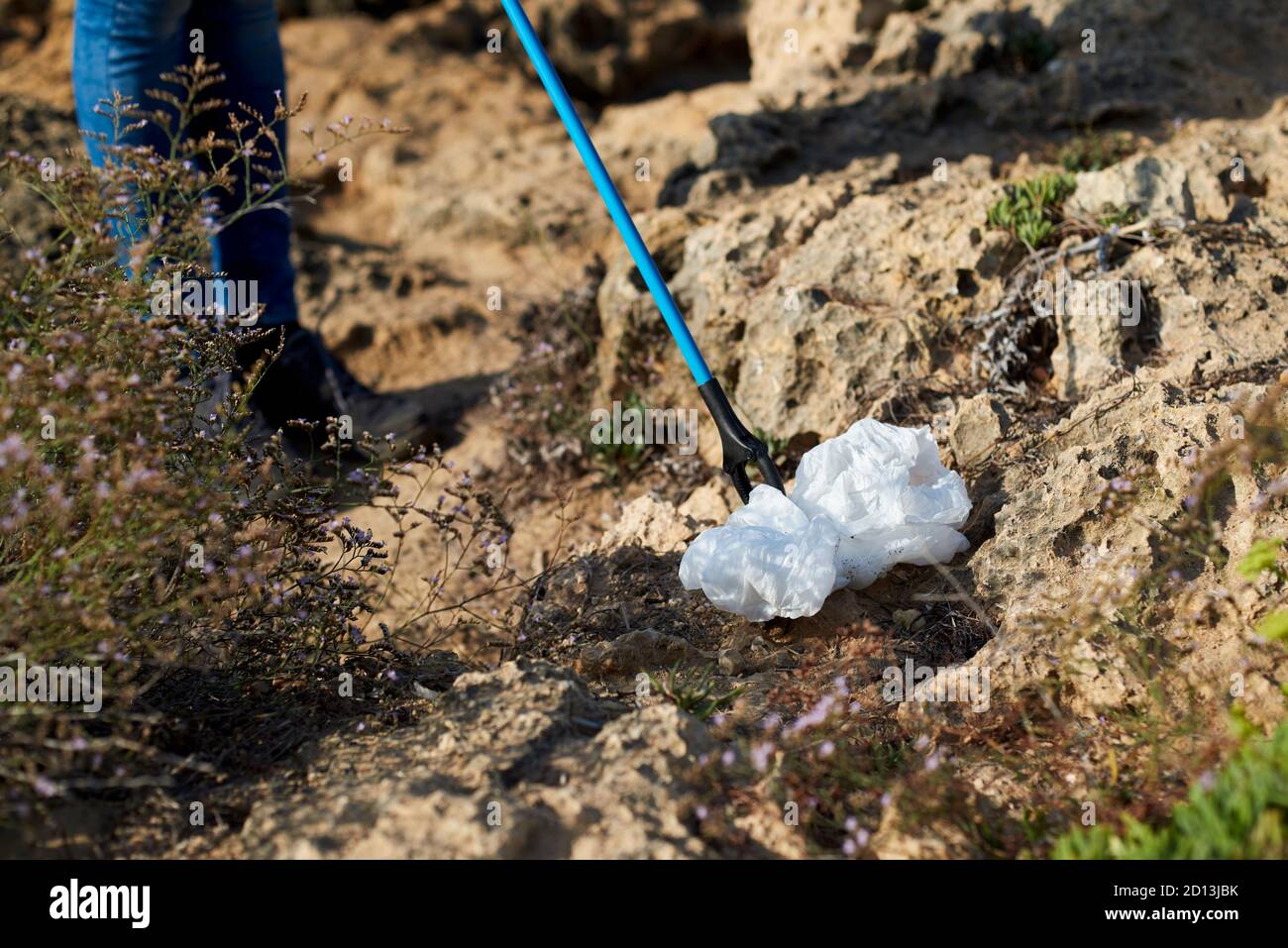 closeup of a caucasian man outdoors collecting garbage with a reach extender, as an action to clean the natural environment Stock Photo