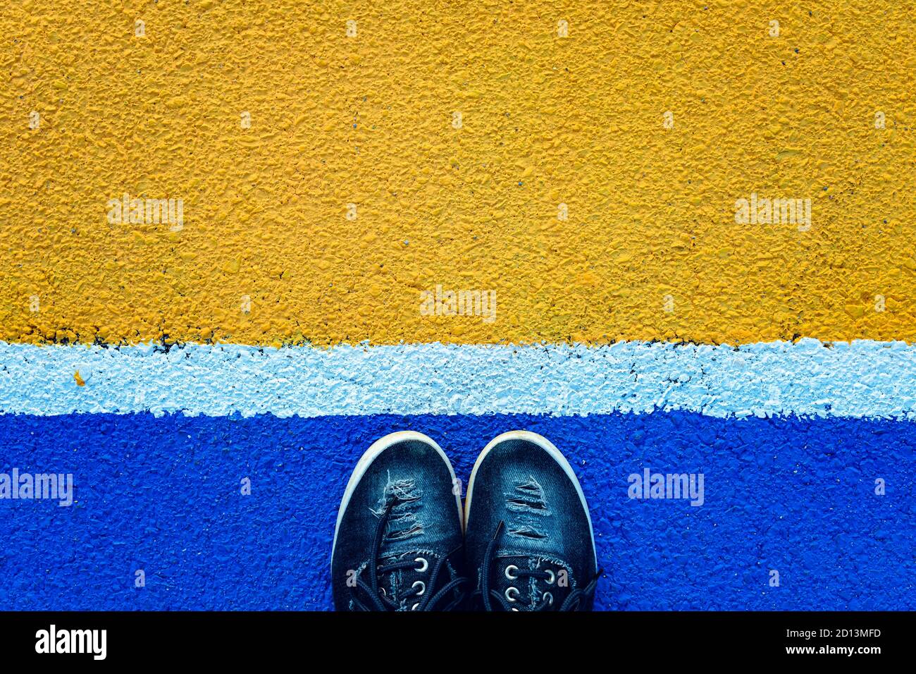 Top view of female legs standing next to the white line on blue