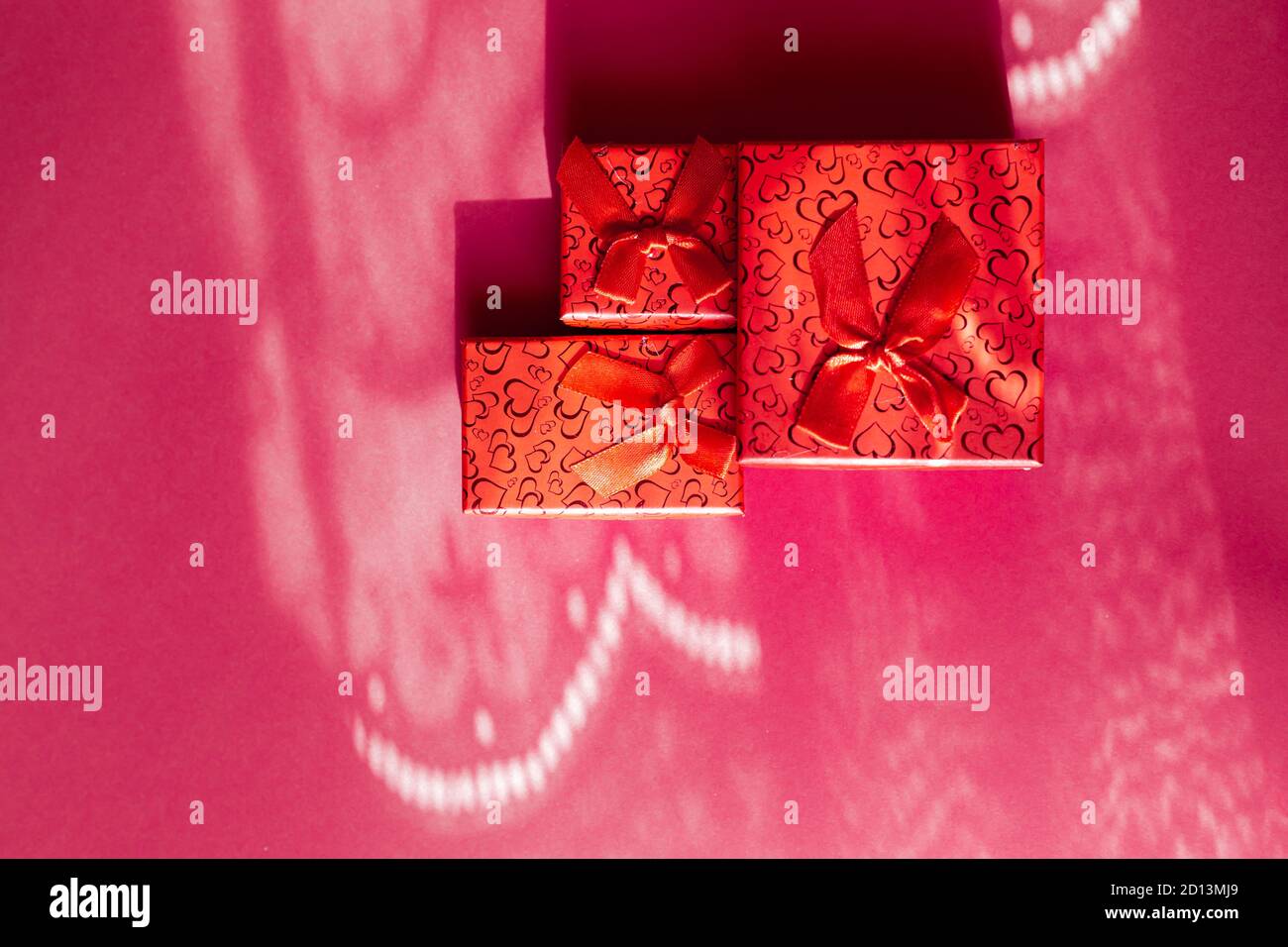 Three red gift boxes in different sizes isolated on pink background ...