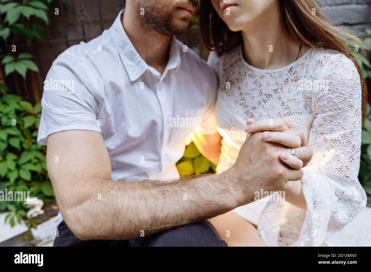 A man and a woman in white clothes embrace. People's hands are