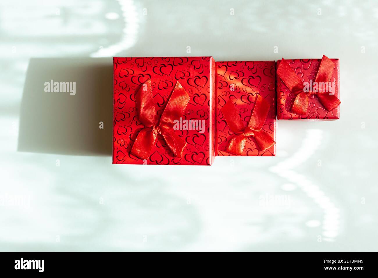 Three red gift boxes in different sizes isolated on blue background Stock Photo