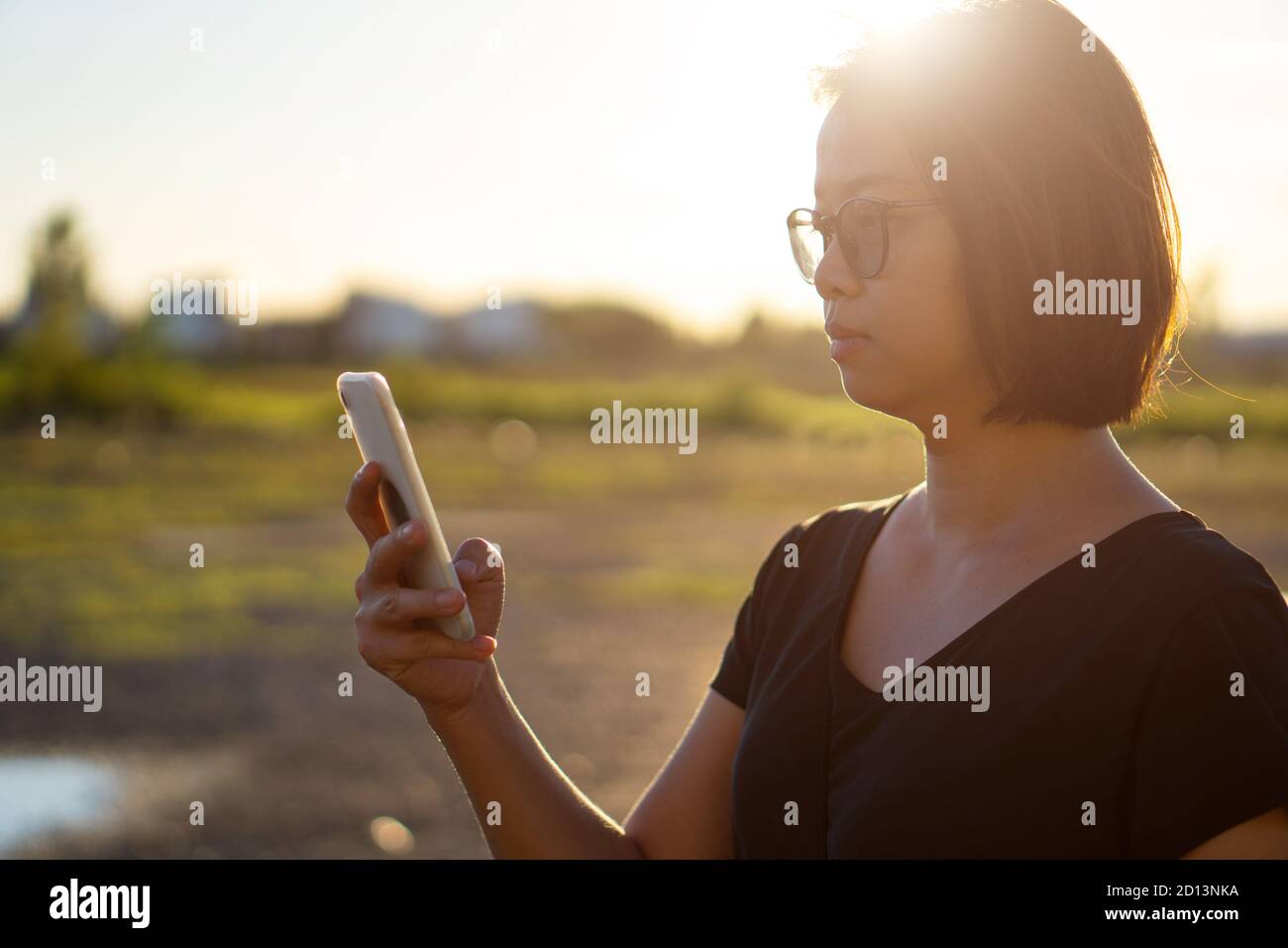 Young asian woman using smartphone at sunset. Stock Photo