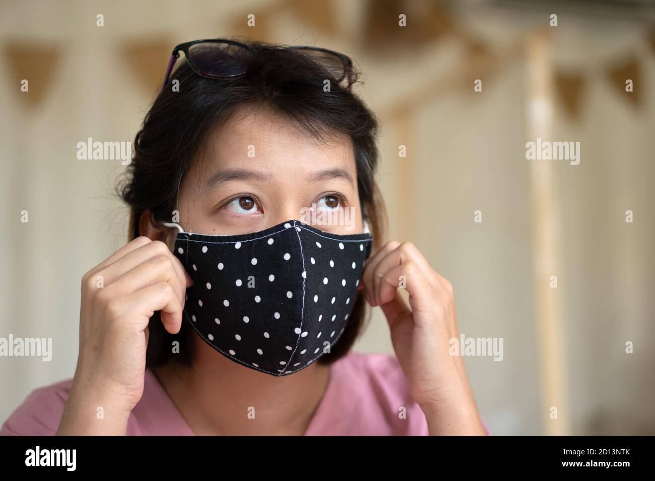 Asian woman wearing protective mask on her face while being in the coffee shop during virus COVID-19 pandemic. Stock Photo