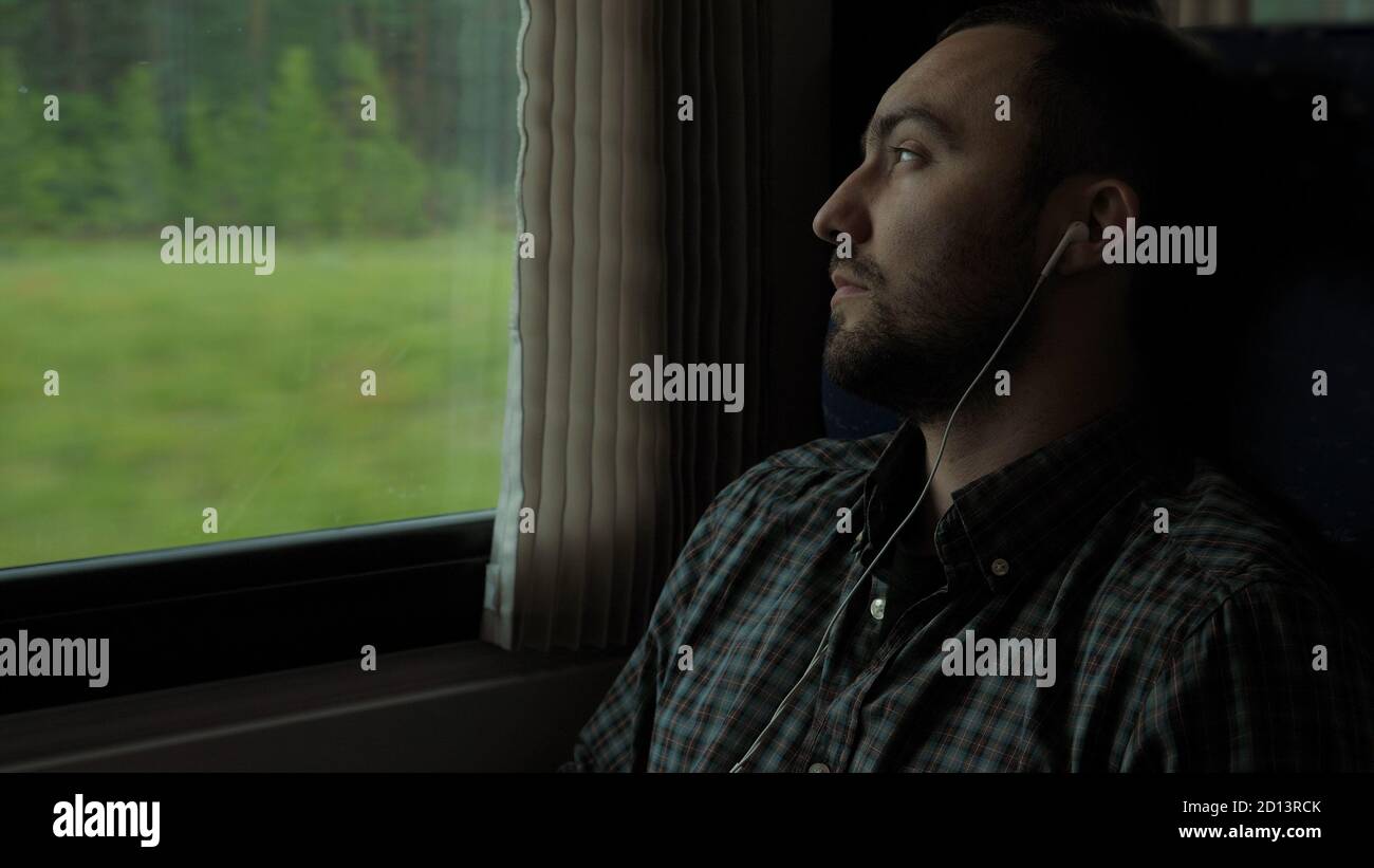 Handsome guy traveling by train, while listening music. Stock Photo