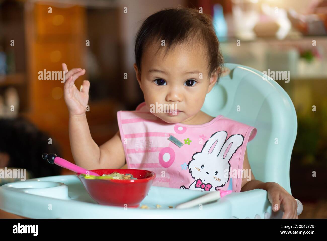 Asian baby girl 11 months year old is eating food on baby table food. Stock Photo