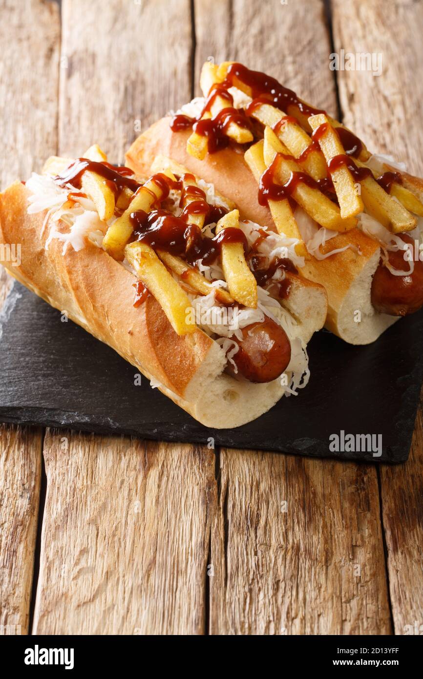 American hot dog polish boy with sausage, cabbage and fries close-up on the table. vertical Stock Photo